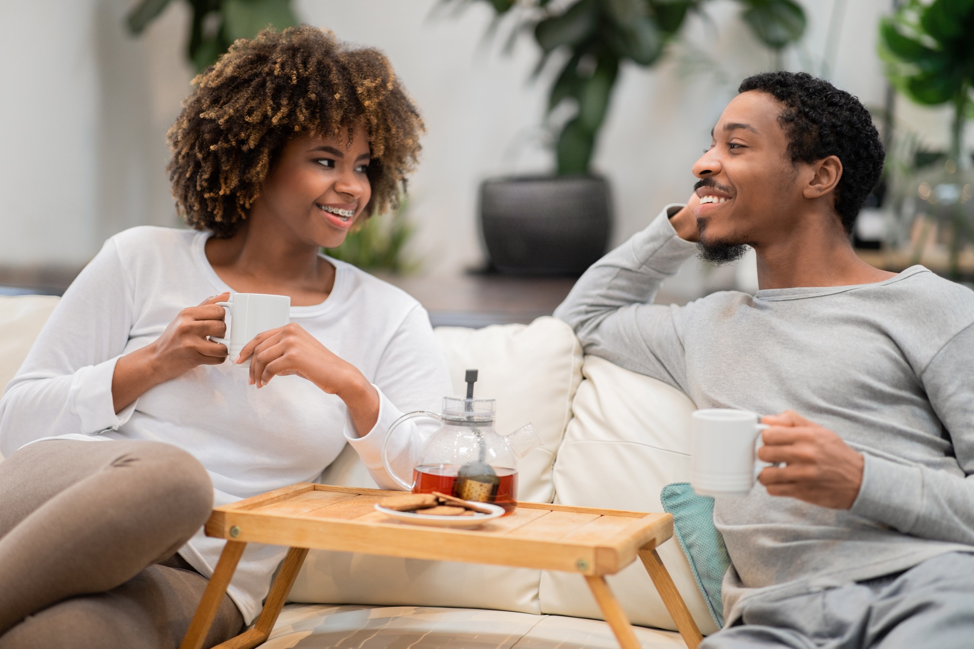 Positive black lovers enjoying tea at home